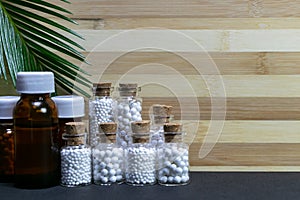 Medicine glass bottles consisting homeopathic substance with green leaf on wood and dark background. Natural medicine concept photo