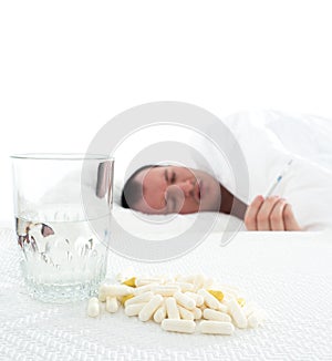 Medicine and a glass of water on the table. the man is lying in bed. disease.