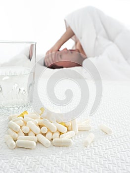Medicine and a glass of water on the table. the man is lying in bed. disease.