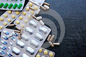 Medicine green and yellow pills or capsules on black background with copy space