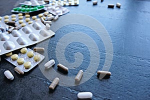 Medicine green and yellow pills or capsules on black background with copy space