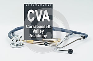 On a white background lies a stethoscope, a pen and a black notebook with the inscription - CVA photo