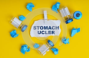 On a yellow background are ampoules, blue crumpled paper and paper with the inscription - STOMACH UCLER photo