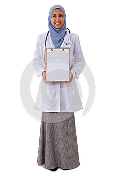 Medicine, healthcare, charity and people concept - smiling muslim female doctor/nurse showing empty blank clipboard sign