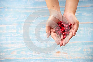 Medicine, healthcare, concept. Closed up hands hold the red medicines or vitamines on the wooden background