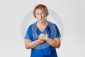 Medicine, healthcare and coronavirus concept. Compassionate redhead female nurse, doctor in scrubs looking with pity photo