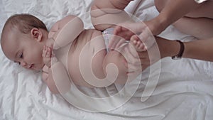 Medicine, healthcare, innocence, pediatrics, infant concepts - mother hands give her newborn child massage on leg, foot