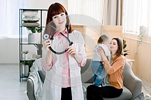 Medicine, healthcare, pediatry and people concept - Attractive female doctor in front of woman with baby, doctor`s visit