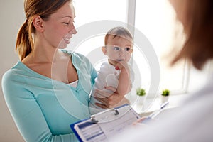 Happy woman with baby and doctor at clinic photo