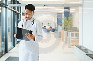 medicine, healthcare and people concept - happy male doctor with stethoscope and clipboard at clinic