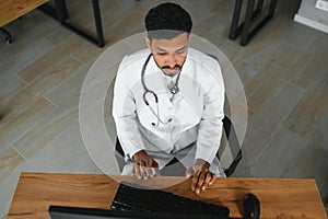 medicine, healthcare and people concept - happy male doctor with stethoscope and clipboard at clinic