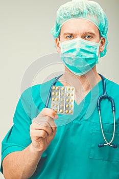 Medicine and healthcare - surgeon holding pills in one hand