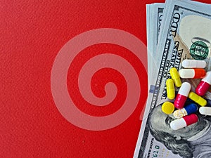 Medicine money pills on dollar bills on red background