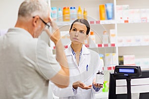 Apothecary showing drug to senior man at pharmacy photo