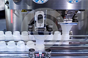 Medicine pill capsules are filling in the white plastic bottle on production line machine conveyor at the medical factory