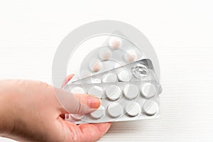 Medicine pills in blister, drug tablets in female hand pattern isolated on white background. Pharmacy and medication.