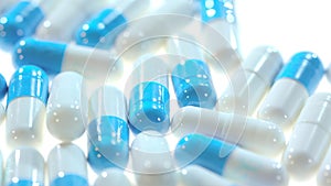 Medicine pills. Close up of white and blue capsules rotating on white table