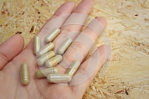 Medicine pills in hand on wooden background.