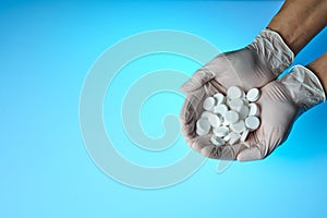 Medicine pills in hands, palm or fingers on blue backgroud. Antibiotic, painkiller closeup. Drug prescription for treatment