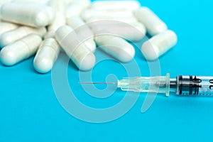 Medicine, pills and insulin syringe on blue background