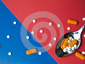 medicine pills, tablets and capsules. Blue and red background. Heap of assorted various medicine tablets and pills on spoon
