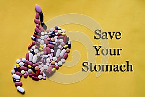 Medicine pills tablets capsules in shape of human stomach in yellow background with space for text