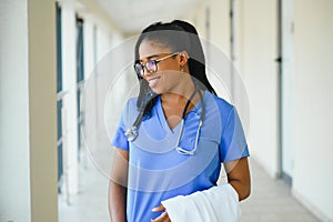 Medicine, profession and healthcare concept - happy smiling african american female doctor with stethoscope over hospital