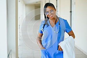 Medicine, profession and healthcare concept - happy smiling african american female doctor with stethoscope over hospital