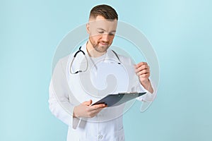 medicine, profession, technology and people concept - happy male doctor with clipboard and stethoscope over blue