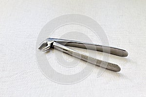 Medicine. Retro. Dental steel forceps for removal of teeth on white gauze background. Black and white photo.