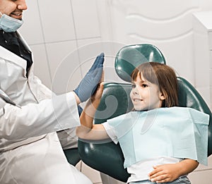 medicine, stomatology and health care concept. Professional young male dentist working with little girl in clinic.