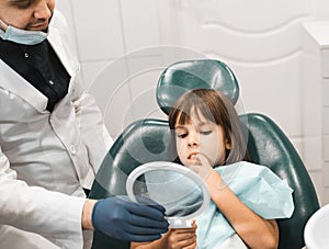 medicine, stomatology and health care concept. Professional young male dentist working with little girl in clinic.