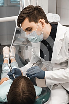medicine, stomatology and health care concept. Professional young male dentist working with little girl in clinic.