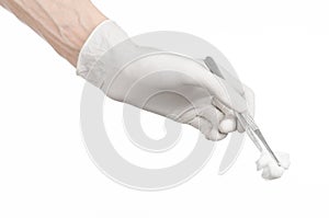 Medicine and Surgery theme: doctor's hand in a white glove holding tweezers with swab isolated on white background in studio