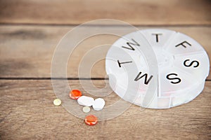 Medicine tablet in pillbox on wood table