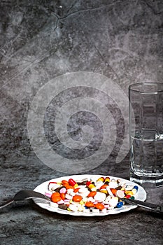 Medicine on a white plate. A bunch of colorful pills disguised as food