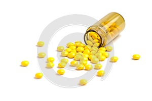 Medicine white and yellow pills or tablets drop out of the brown glass bottle on white background. Isolate