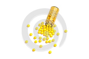 Medicine yellow pills drop out of the brown glass bottle on white background
