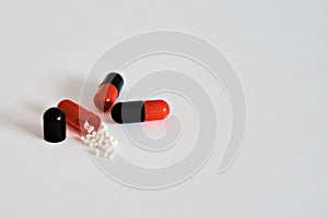 Medicines in black-red capsules. One capsule is opened and the substance that fills it is visible. Concept of medicine