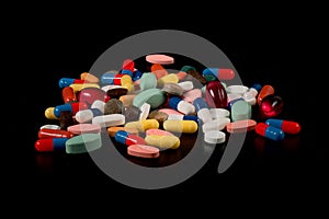 Medicines in capsules of many colors on a black background