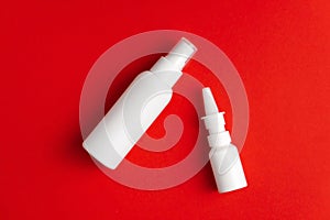 Medicines for treatment of nose and throat. Nasal and throat spray bottles on red background. Mockup