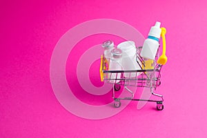 Medicines, drops in a metal trolley for a buyer from a supermarket on a pink paper background. The concept of medicine and the