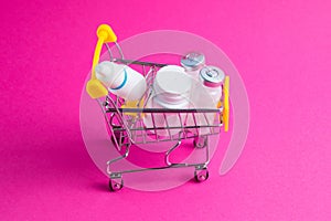 Medicines, drops in a metal trolley for a buyer from a supermarket on a pink paper background. The concept of medicine and the