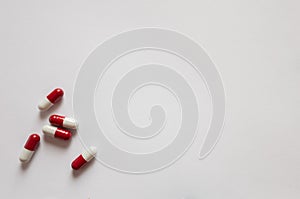 Medicines, pills. Medical background, red-white capsules on a white background. Top view of pills on white surface