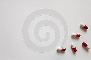 Medicines, pills. Medical background, red-white capsules on a white background. Top view of pills on white surface