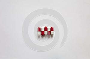 Medicines, pills. Medical background, red-white capsules on a white background. Top view of pills on white surface
