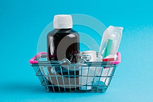 Medicines in a shopping cart for a shopper from a supermarket on a blue paper background. The concept of medicine and the cost of