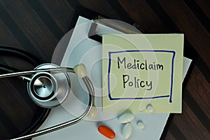 Mediclaim Policy write on sticky notes isolated on Wooden Table. Medical or Healthcare concept