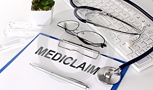 MEDICLAIM text on white paper on white background. stethoscope ,glasses and keyboard