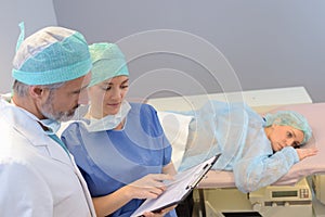 Medics looking at notes patient face down on bed